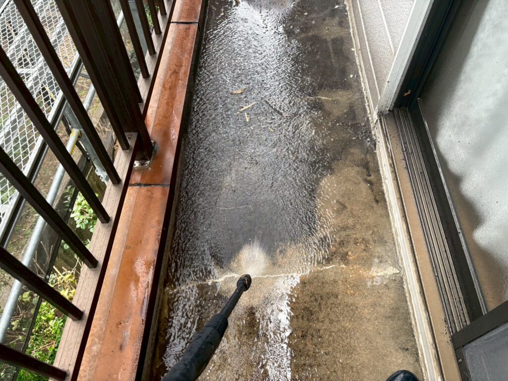 バルコニーの床を高圧洗浄機で洗い流している写真