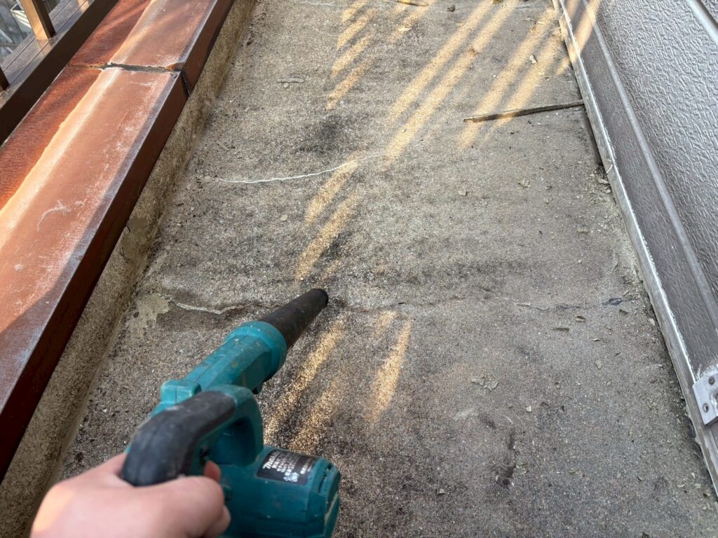 バルコニー床をブロワーで吹き飛ばしている写真